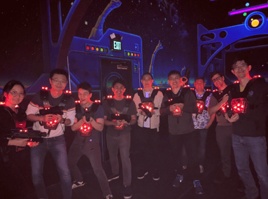 Nine people holding laser tag guns at a laser tag event